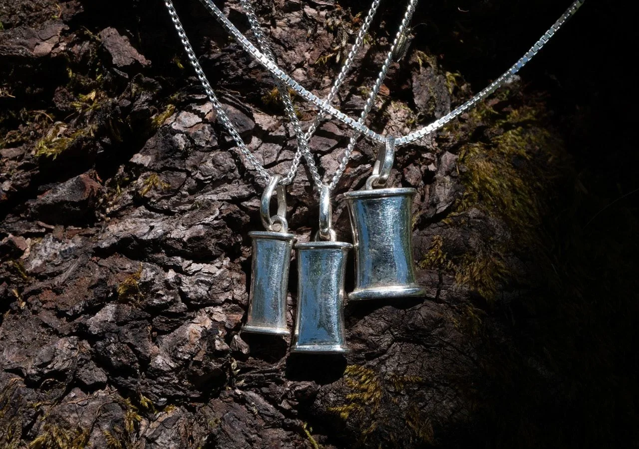 Three Breathing Jewel sterling silver pendant sizes displayed together on tree bark